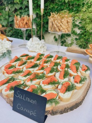 Lachs-Canapés auf einer Holzscheibe mit handgeschriebenem Schild