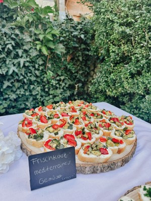 Canapés mit Tomate und Frischkäse vor einer Efeuwand